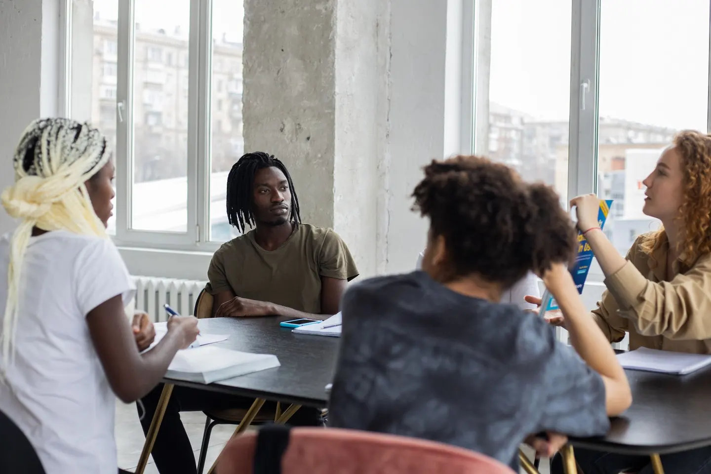 A group discussing open notebooks around a table in a bright room.