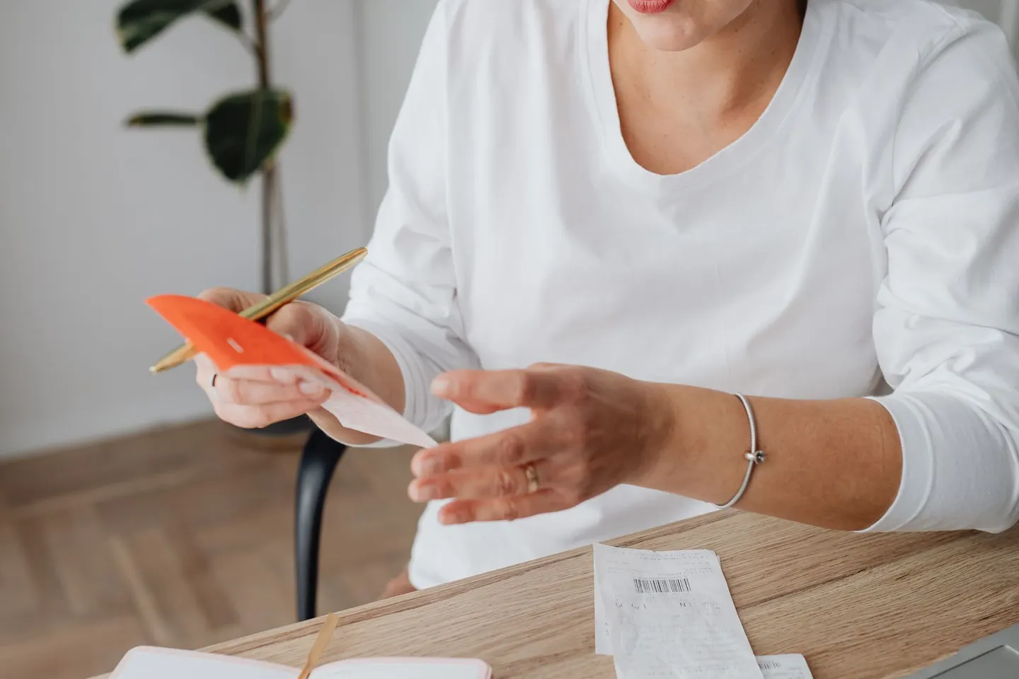 A woman checking receipts with a calculator at a wooden desk.