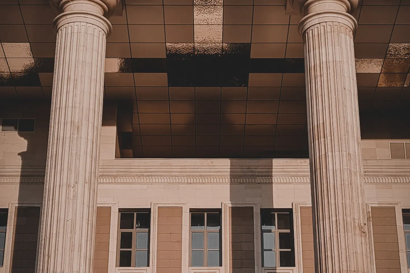 Tall stone columns frame a building facade with rows of narrow windows.