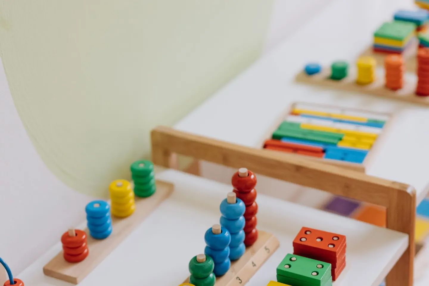 Colorful wooden counting toys and a small xylophone sit on low wooden tables.