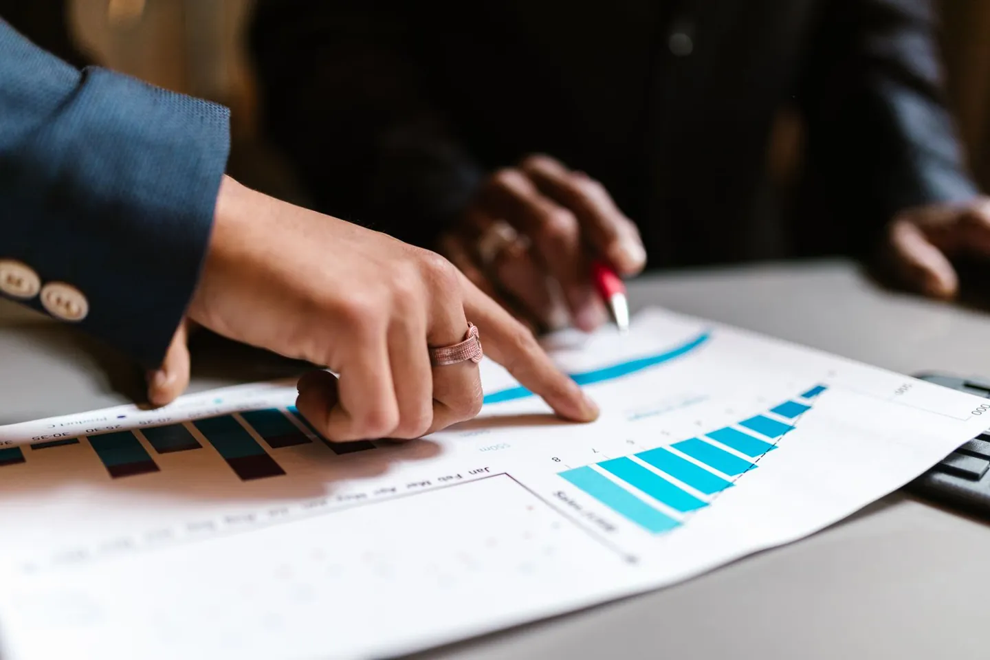 Two people review printed bar and line charts at a table.