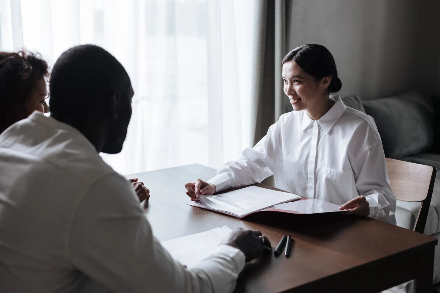 Three people discuss documents together at a table.