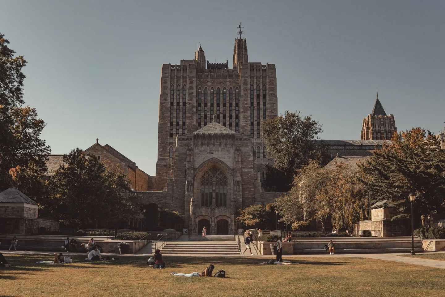 Students rest on the lawn in front of the Gothic Sterling Memorial Library at Yale University in New Haven, Connecticut.