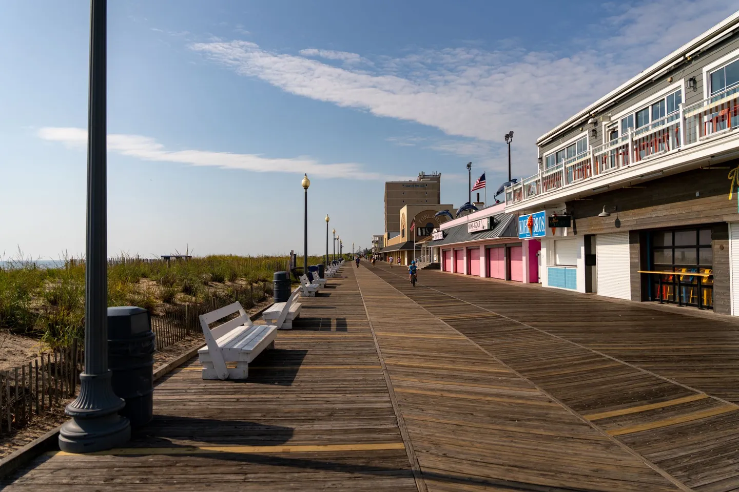 The wooden Rehoboth Beach boardwalk and shops on a sunny day in Delaware.