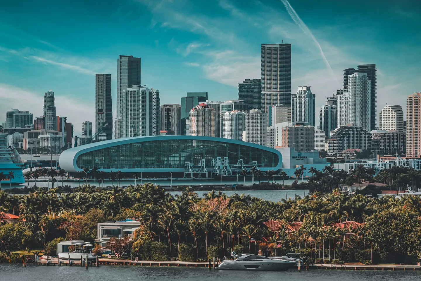 The Miami skyline rises behind palm-lined waterfront homes in Florida.