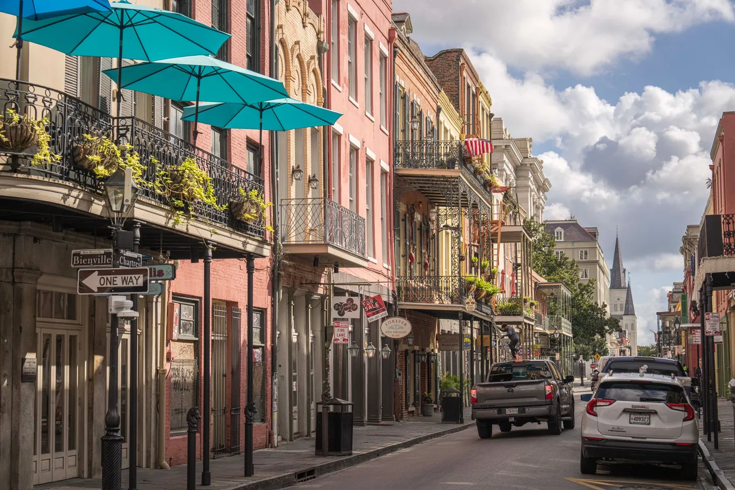 Balconies and pastel buildings line a street in the French Quarter of New Orleans, Louisiana.