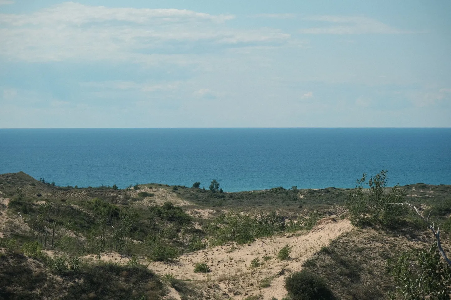 Grassy sand dunes slope down to the blue water of Lake Michigan near Maple City, Michigan.