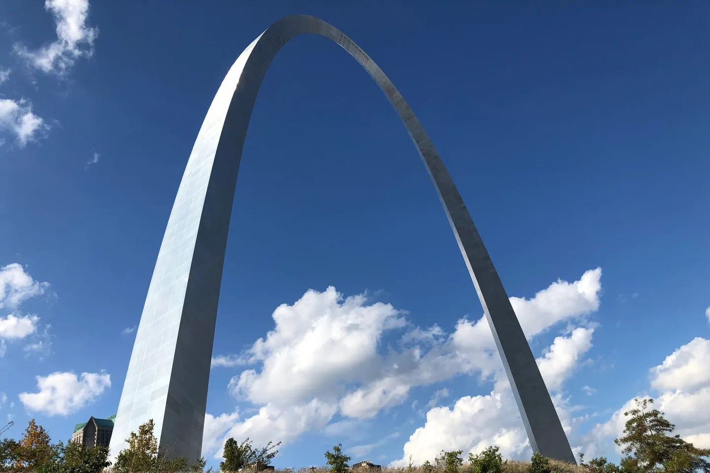 The Gateway Arch in St. Louis rises against a bright blue sky with clouds in Missouri.