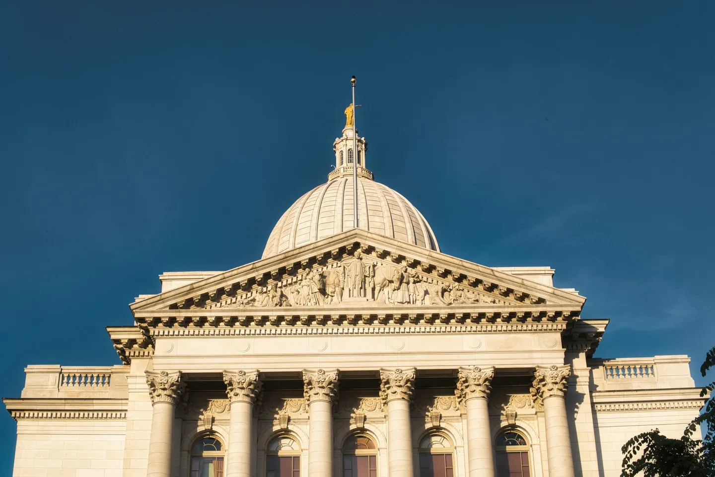 The Wisconsin State Capitol dome and columned facade against a deep blue sky in Madison, Wisconsin.